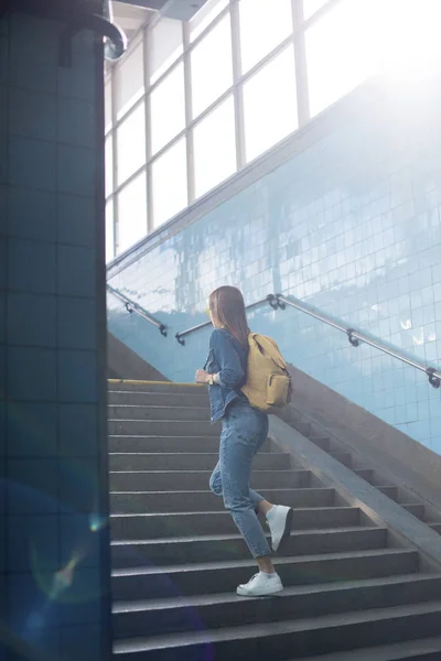 Rear view of female tourist with backpack going upstairs at subway — Stock Photo