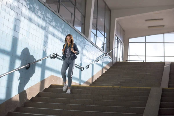 Young stylish female tourist with backpack going downstairs at subway — Stock Photo