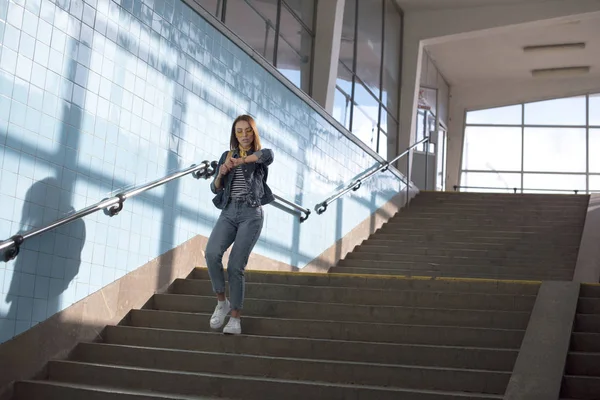 Stylische Touristin schaut auf Armbanduhr und geht in der U-Bahn die Treppe hinunter — Stockfoto