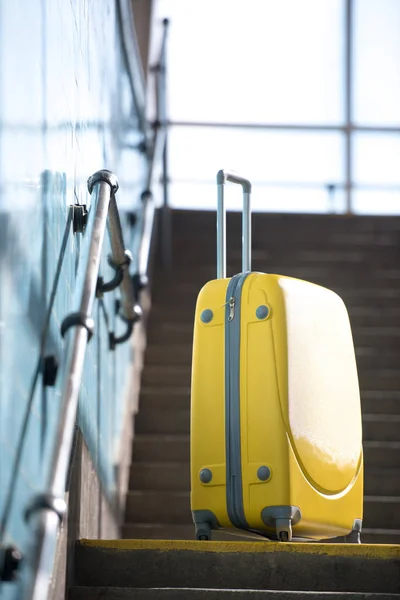 Gros plan de sac à roulettes jaune dans les escaliers du métro — Photo de stock