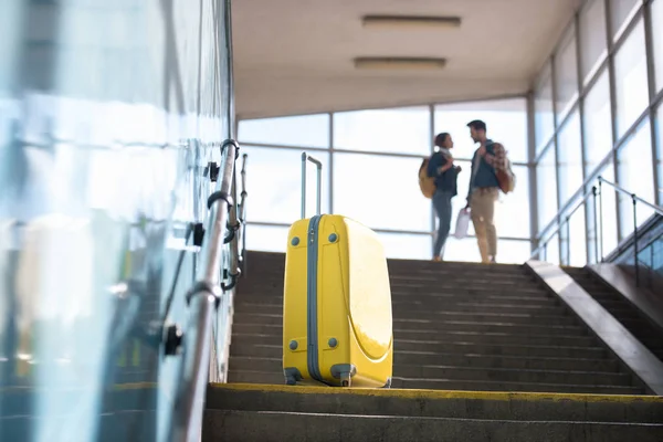Низкий угол зрения на колёсную сумку и пару туристов, говорящих позади в метро — стоковое фото