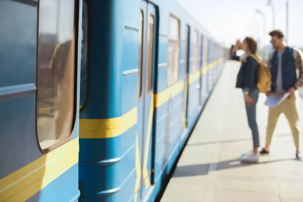 Closeup shot of train and couple of tourists behind at outdoor subway station — Stock Photo