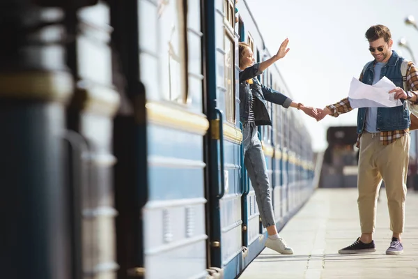 Male tourist looking at map and girlfriend waving by hand at outdoor subway station — Stock Photo