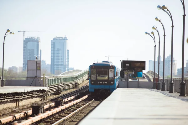 Arriving train at outdoor subway station with buildings on background — Stock Photo