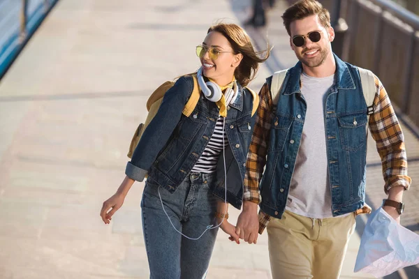 Пара стильних туристів в сонцезахисних окулярах з рюкзаками, навушниками та картою на відкритій станції метро — стокове фото