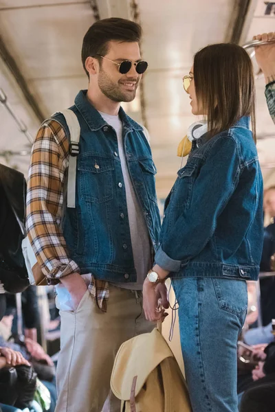 Casal elegante de turistas em óculos de sol falando em trem de metrô — Fotografia de Stock