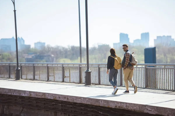 Fernsicht auf ein paar stylische Touristen mit Rucksäcken, die an einer U-Bahn-Station im Freien unterwegs sind — Stockfoto