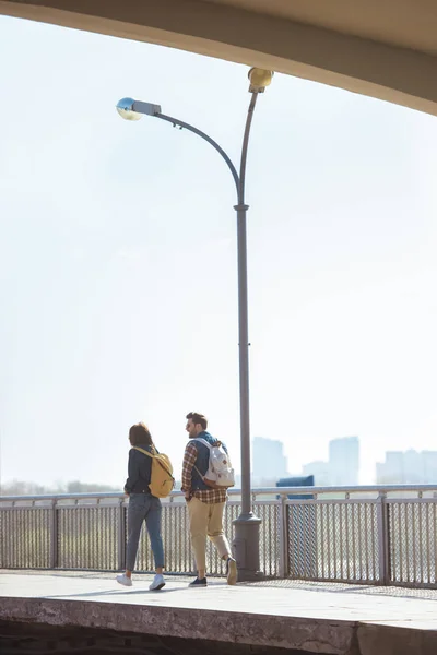 Vista trasera de un par de turistas que van en la estación de metro al aire libre - foto de stock