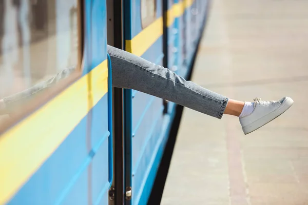 Colpo ritagliato di gamba femminile guardando fuori dal treno alla stazione della metropolitana all'aperto — Foto stock