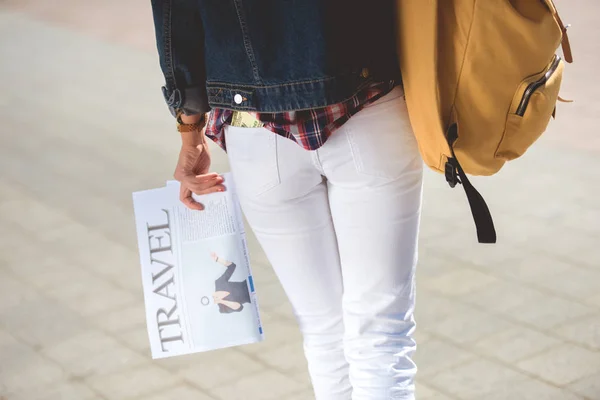 Imagen recortada de turista femenina con estilo con mochila y periódico de viajes - foto de stock