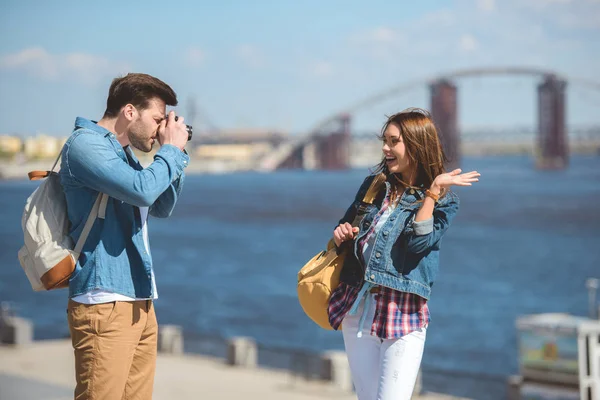 Visão lateral do viajante masculino com mochila atirando sorrindo namorada na câmera — Fotografia de Stock