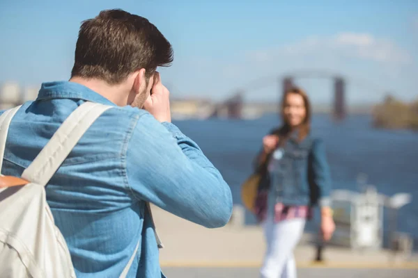 Вид ззаду чоловіка мандрівника з рюкзаком стрілянина дівчина на камеру — стокове фото