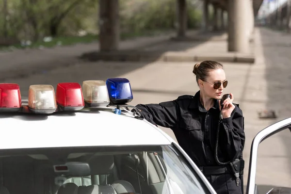 Policewoman talking by radio set near patrol car — Stock Photo