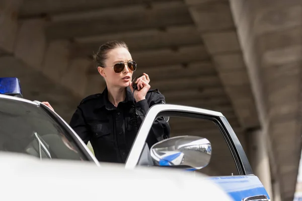 Policewoman talking by radio set near police car — Stock Photo