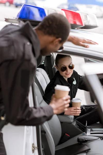 Young police officers with car drinking coffee to go — Stock Photo