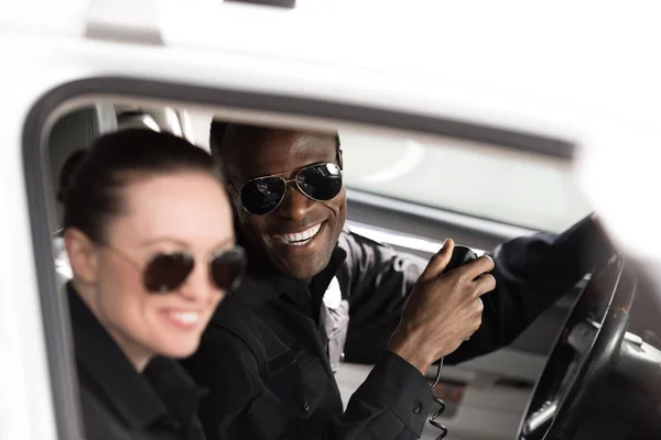 Close-up shot of smiling police officers sitting in police car — Stock Photo