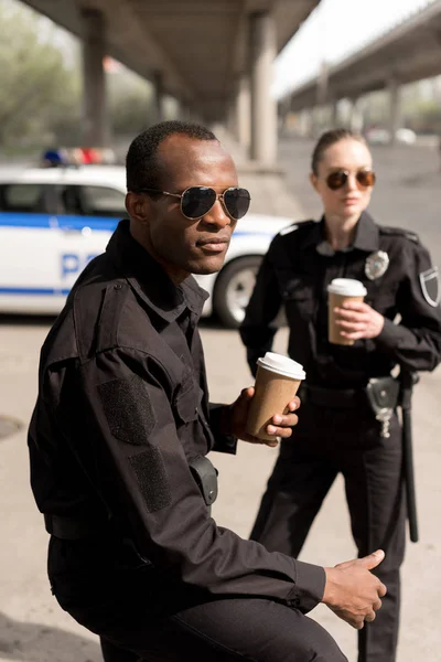 Serious young police officers having coffee break — Stock Photo
