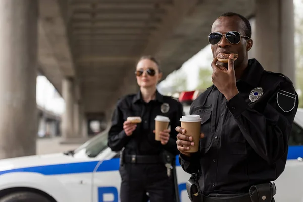 Jeunes policiers en pause café avec beignets devant la voiture de police — Photo de stock