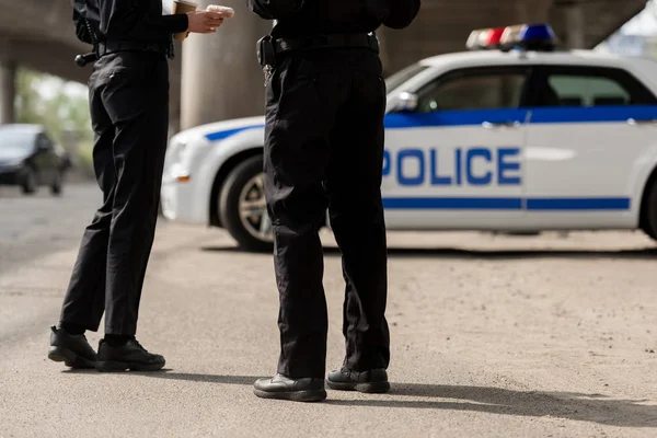 Coup de feu recadré de policiers debout devant la voiture de police — Photo de stock