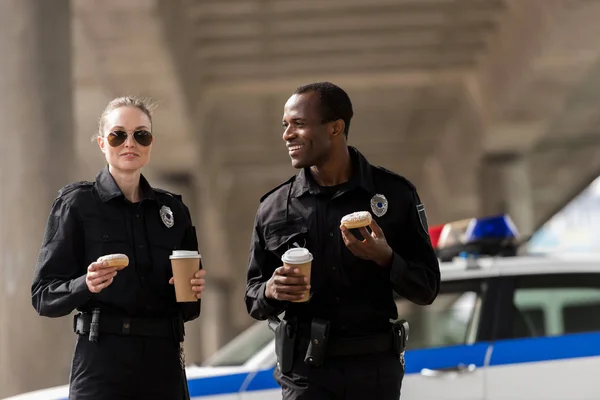 Des policiers souriants prenant une pause café avec des beignets — Photo de stock