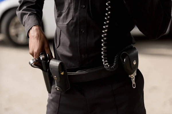 Tiro cortado de policial em uniforme tirando arma — Fotografia de Stock