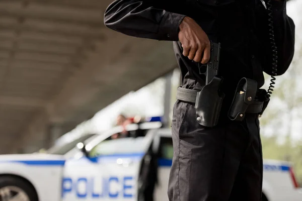 Colpo ritagliato di agente di polizia che tira fuori la pistola — Foto stock