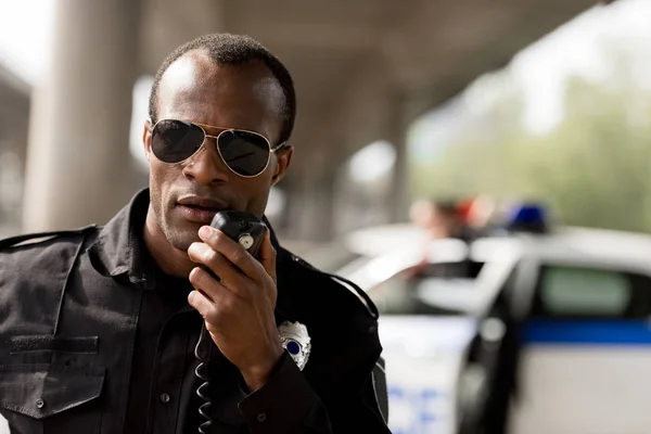 Policía afroamericana hablando por radio walkie-talkie - foto de stock