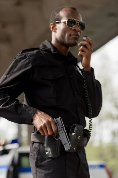 Agente di polizia parlando da walkie-talkie radio set e pistola in mano — Foto stock