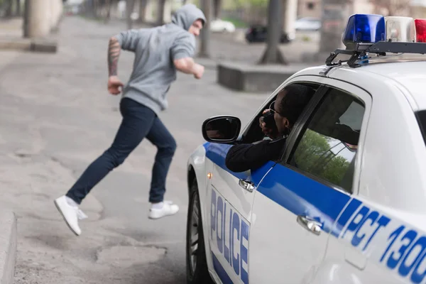 African american policeman on car chasing thief — Stock Photo