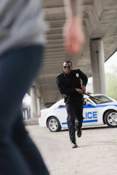 Cropped shot of thief running from african american policeman — Stock Photo