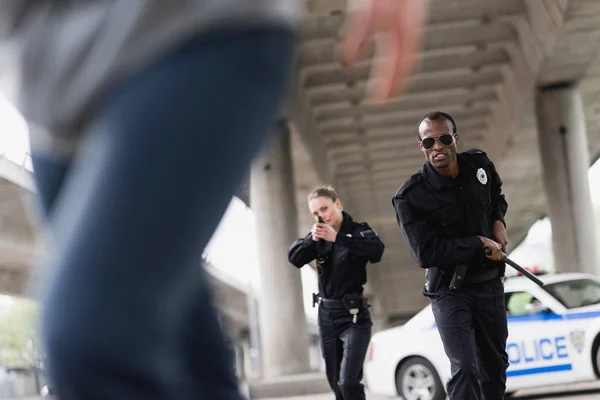 Multiethnic young police officers running for thief — Stock Photo