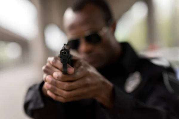 Close-up tiro de arma nas mãos do policial afro-americano — Fotografia de Stock