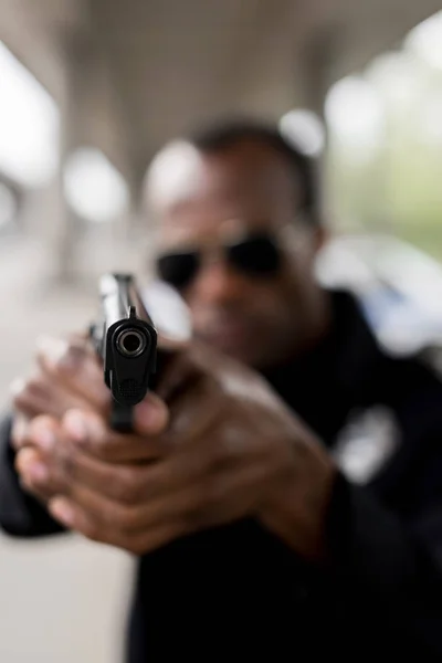 Primer plano de la pistola negra en las manos del policía - foto de stock