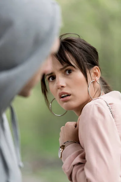 Scared young woman looking at thief in hoodie — Stock Photo