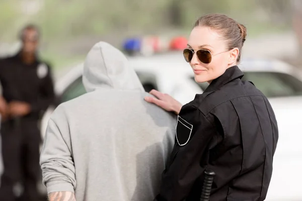 Lächelnde Polizistin mit Sonnenbrille und verhaftetem Kriminellen — Stockfoto