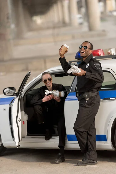 Happy african american policeman with female partner having lunch — Stock Photo