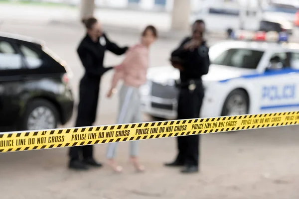 Closeup shot of cross line and police officers arresting woman on blurred background — Stock Photo