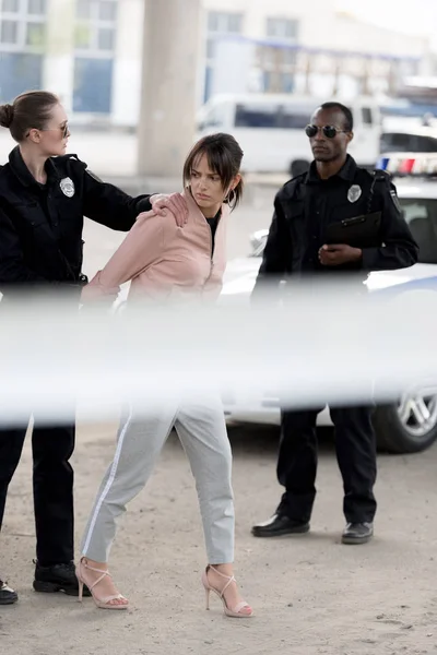 Policière détention femme arrêtée alors que policier debout près de — Photo de stock