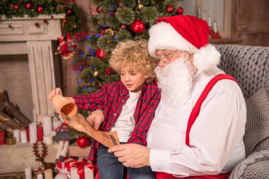 Santa Claus and child reading wishlist clipart
