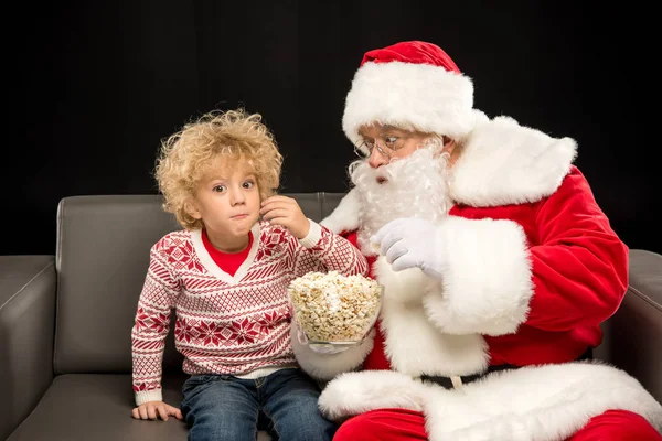 Weihnachtsmann isst Popcorn mit Kind — Stockfoto