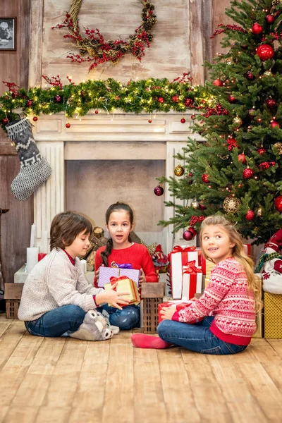 Crianças sentadas no chão com presentes de Natal — Fotografia de Stock