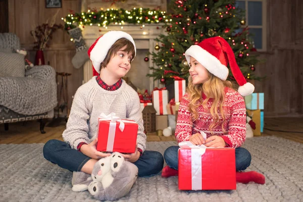 Kinder in Weihnachtsmützen mit Weihnachtsgeschenken — Stockfoto