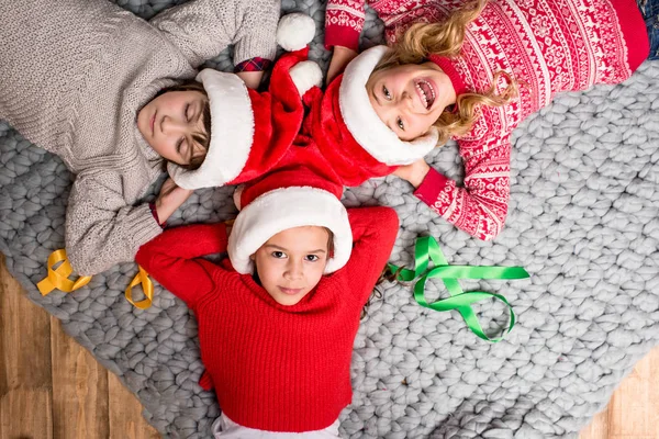 Kinderen in Santa hoeden liggen in cirkel — Stockfoto