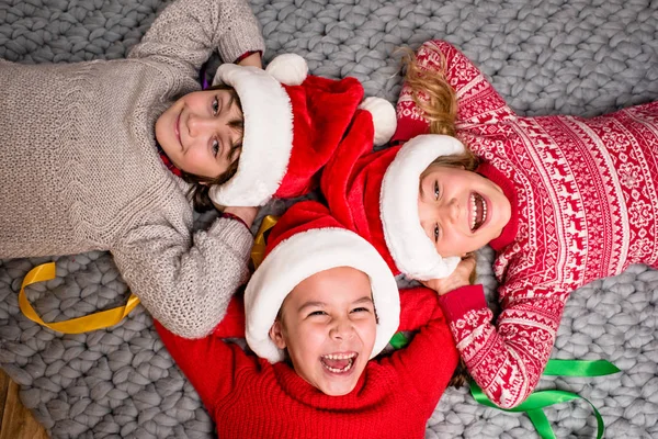 Děti v Santa klobouky leží v kruhu — Stock fotografie