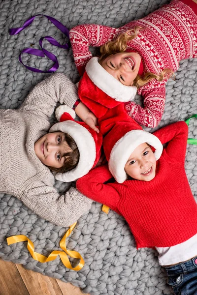 Kinder mit Weihnachtsmützen liegen im Kreis — Stockfoto