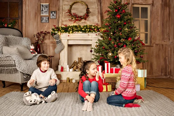 Kinderen zitten op tapijt met giften van Kerstmis — Stockfoto