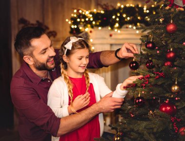 Baba ve kızı Noel ağacı süslüyorlar.  