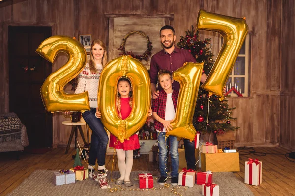 Happy family holding golden balloons — Stock Photo, Image