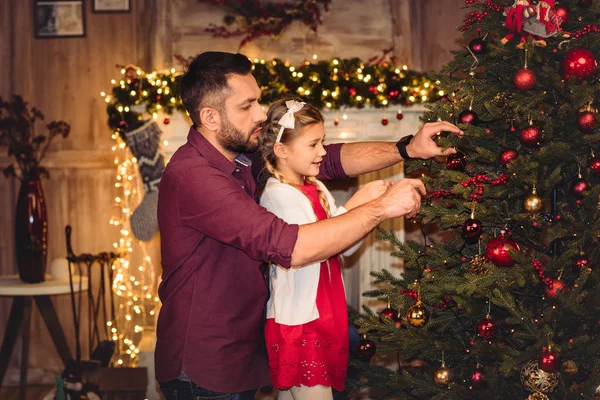 Baba ve kızı Noel ağacı süslüyorlar. 
