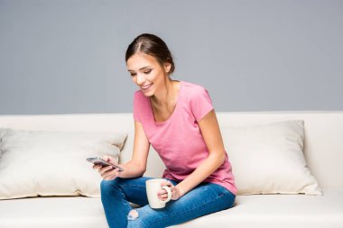 Smiling woman using smartphone clipart